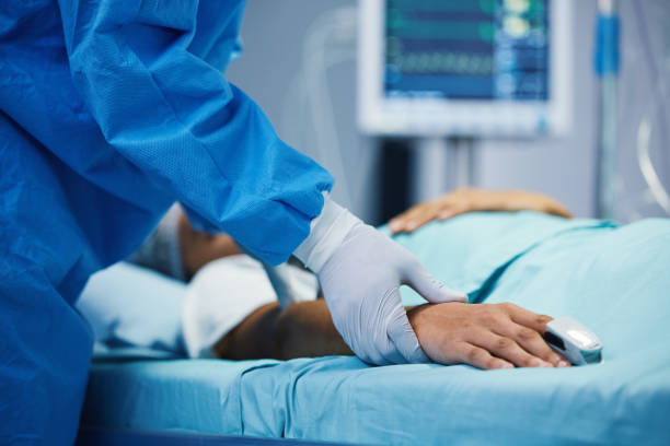 Holding hands, healthcare and a doctor with a patient in surgery for pulse, help or support. Hospital, medicine and closeup of a surgeon in theater with a person for consultation or medical nursing stock photo