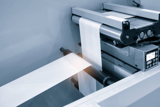 istock Automatic industrial machine for plastic packaging with light effect of products and food. shaft of an automated packaging line with plastic film in a light blue scene. product packaging concept 1560114595