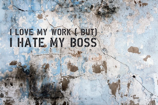 Old dirty grunge grunge cracked wall with text I LOVE MY WORK BUT I HATE MY BOSS , concept of feeling exhausted and drained working with toxic people or a bully narcissist team leader