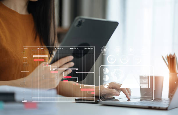 istock Woman hand Project manager working and update tasks and Gantt chart scheduling virtual diagram.with smart phone, tablet and laptop in office. 1560120067