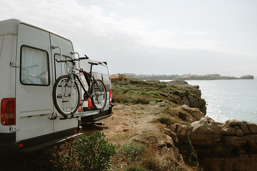 A camper van with a mountain bike parked by the sea