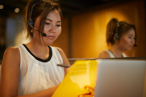 Kazakh young lady customer representative talking on the headset in a modern office