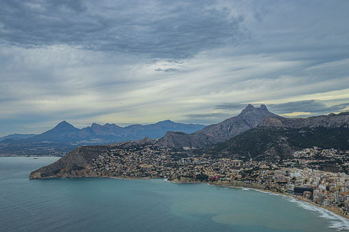 Scenic view over the Calpe bay from the top of the Ifach rock, mountains, hills, forests and houses, Alicante