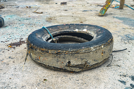 a used car tire that is damaged and unused on the beach