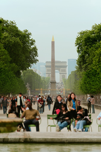 Paris, France - May 22, 2023: Grande Allée of the Tuileries Garden, looking towards the Place de la Concorde and the Arc de Triomphe. The Tuileries Garden (French: Jardin des Tuileries) is a public garden located between the Louvre and the Place de la Concorde in the 1st arrondissement of Paris, France. Created by Catherine de' Medici as the garden of the Tuileries Palace in 1564, it was eventually opened to the public in 1667 and became a public park after the French Revolution. Since the 19th century, it has been a place where Parisians celebrate, meet, stroll and relax.
