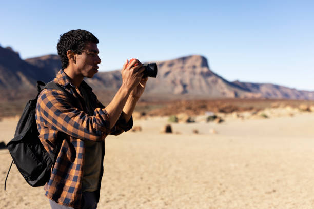 istock Young man taking pictures on a road trip. 1560172591