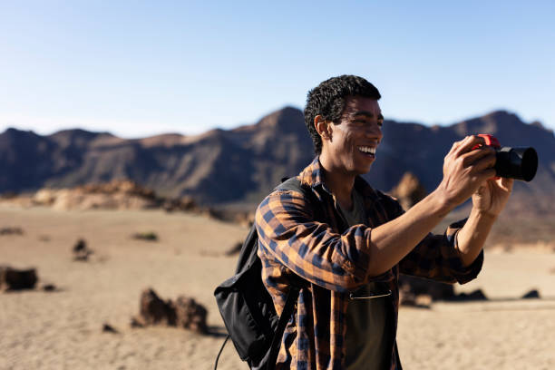 istock Young man taking pictures on a road trip. 1560172854