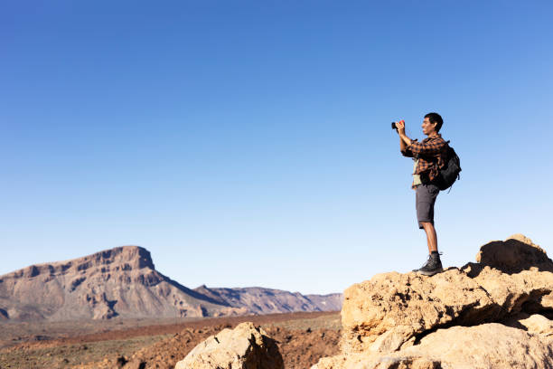 istock Young man taking pictures on a road trip. 1560173406