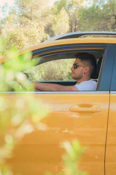 istock Latino man drives yellow car down a road 1560176171