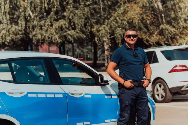 A policeofficer patrols the city. A police officer with sunglasses patroling in the city with an official police car.