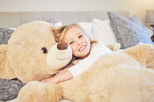 Little cute caucasian girl hugs her favorite toy big teddy bear. Love and tenderness. Happy childhood concept. Gift for a birthday or other holiday