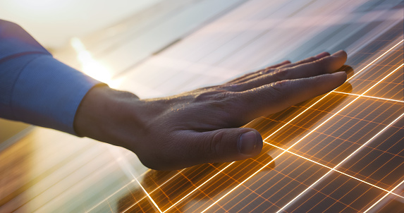 Close Up on Hand Of Professional Maintenance Engineer Touching Industrial Solar Panel Generating Electricity. VFX Graphics Edit Visualizing Energy Being Generated. Green Energy Concept.