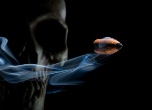 Photo of smoke coming out from human skull in front of orange background for halloween. Shot with a full frame mirrorless camera.