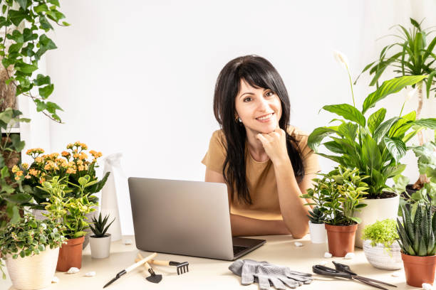 Smiling female using laptop computer at workshop transplantation houseplants