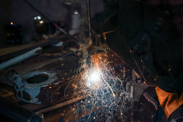 soudage d’une vieille pièce de voiture en métal à l’atelier, étincelles et fumée volant, détail en gros plan - manufacturing occupation photos et images de collection