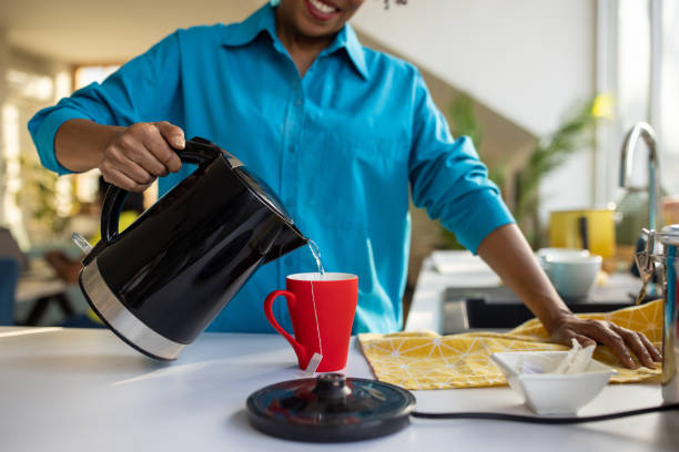 istock Woman pouring hot water into a cup to make tea 1560218989