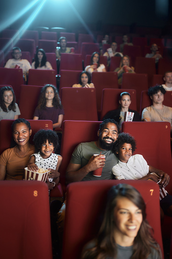 Happy African American family and group of people enjoying while watching a movie in cinema.