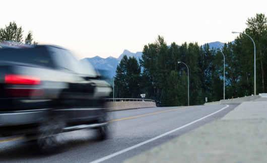 A motion blurred pick up truck heading towards the mountains for a vacation.