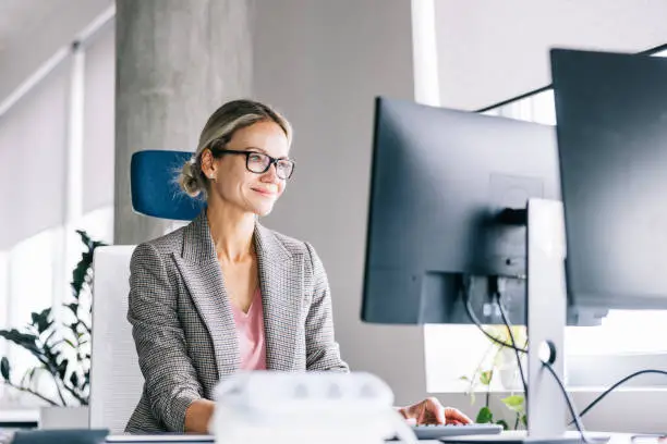 Portrait of positive looking businesswoman working a the office. She's enjoying her financial work duties.