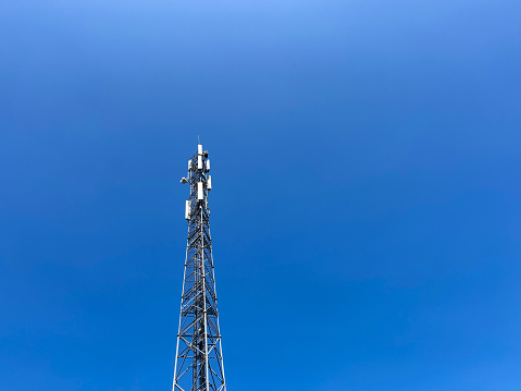 Telecommunication tower with 5G cellular network antenna against stormy sky with clouds