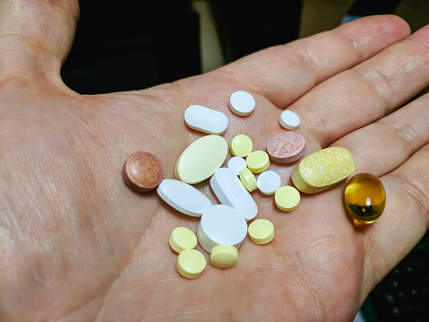 A man holds a large number of tablets medication in his hand.