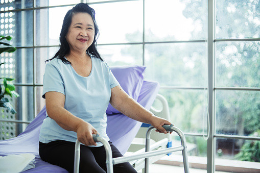 Portrait of senior Asian woman sitting on bed and recovering from illness