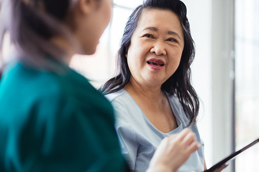 Home healthcare nurse explaining medication to senior woman at home