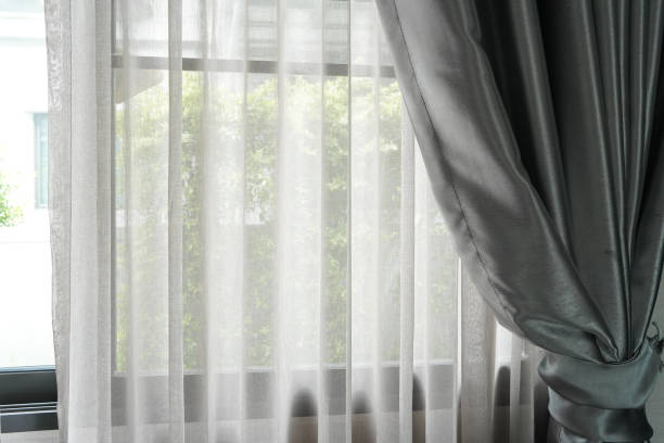 istock Beautiful curtains on window in stylish room interior green tree outside window. 1560300757