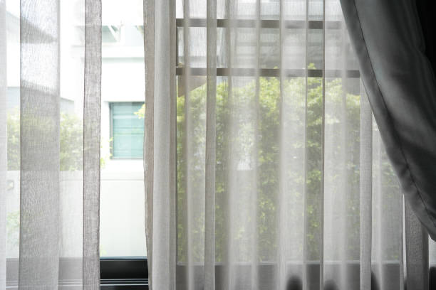istock Beautiful curtains on window in stylish room interior green tree outside window. 1560301275