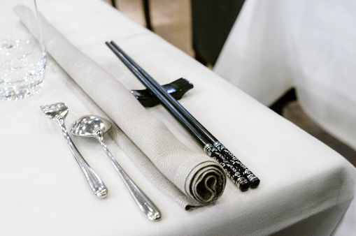 Chopsticks beside western silverware cutlery in an upmarket restaurant
