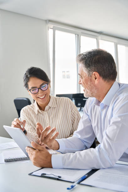 istock Two happy professional business people workers using digital tablet in office. 1560352600