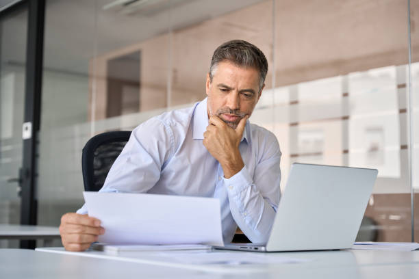 istock Serious mid aged business man checking financial documents thinking. 1560354741