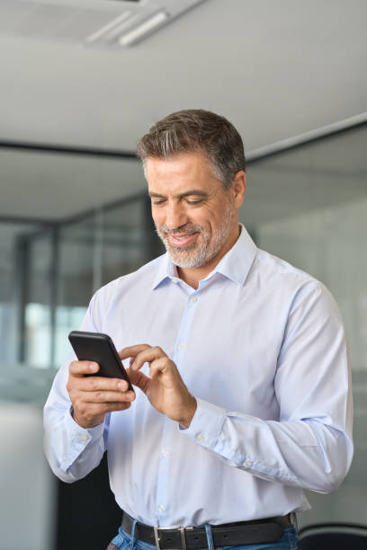 istock Mature business man office employee standing using cell phone. 1560355710
