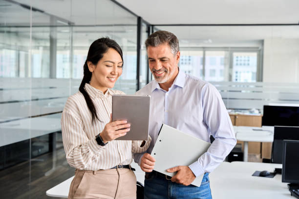 istock Two happy professional business people workers using digital tablet in office. 1560355863