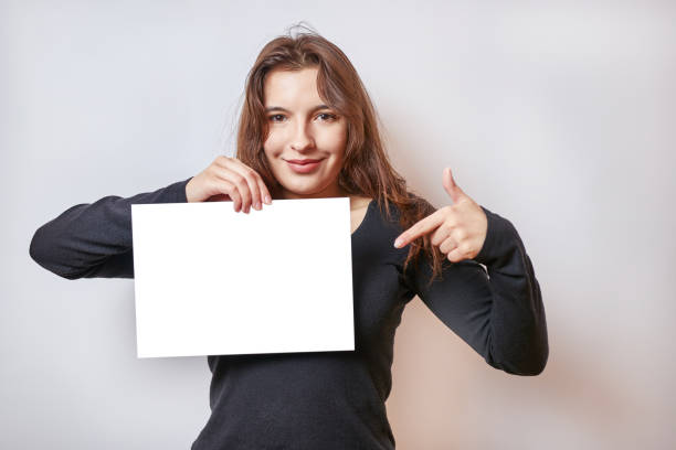 istock Pretty girl holding a banner, white billboard. 1560358036