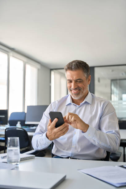istock Happy mature business man manager using mobile phone at work in office. 1560358043