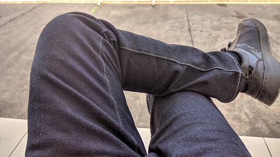 the feet of a man wearing raw jeans. Raw jeans are one type of pants