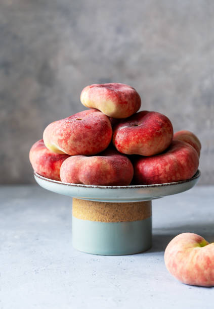 istock Flat or donut peaches in green grey ceramic cake stand on grey concrete background, place for text, vertical banner 1560401104