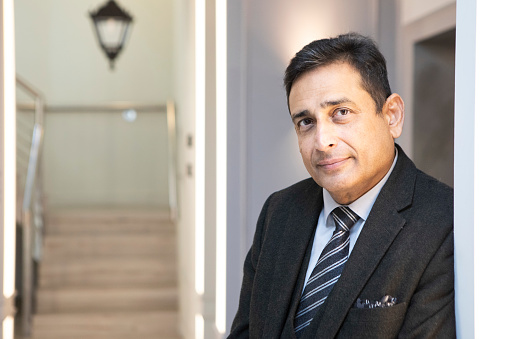 Portrait of a Handsome Businessman Wearing a Suit, Posing with American Flag in the Background. Successful Middle Aged Male Smiling, Looking at Camera. Concept of US Politics, Government Elections