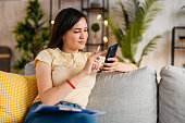 Young Woman Checking Her Finances On The Phone At Home