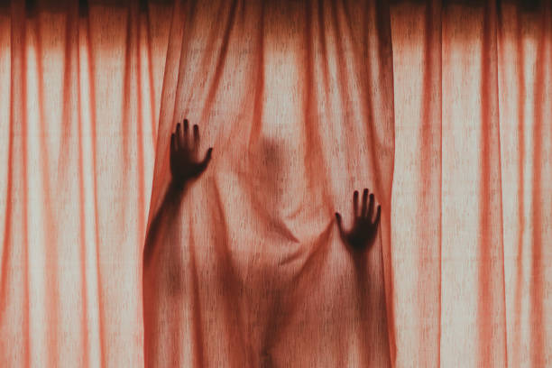 Young woman opening curtain at home