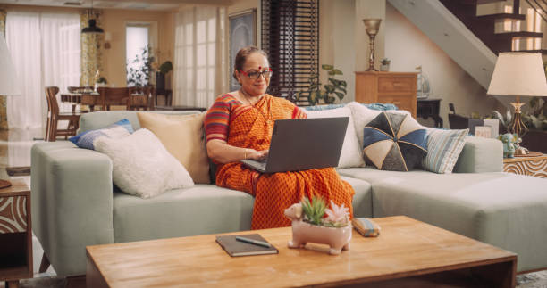 Indian Elderly Woman Using Laptop at Home: Exploring Online Information, Enjoying Entertainment, and Expanding Knowledge. Embracing Technology for Personal Growth. Medium Shot.