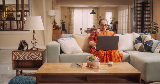 istock Elderly Indian Woman Using Laptop at Home: Immersed in Captivating Online Stories, Exploring New Ideas, NurturingLifelong Love for Learning. Celebrating the Beauty of Curiosity of Old Age. 1560454932