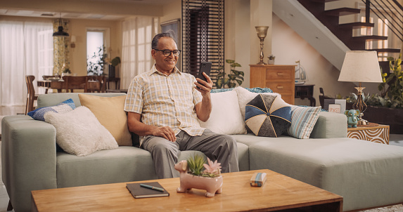 Elderly Indian Man Using Smartphone for Video Call: Cherishing Talks with Loved Ones, Engaging in Meaningful Conversations, and Celebrating Family.Active Grandfather Stays Connected.