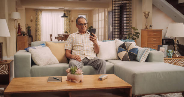 istock Elderly Indian Man Using Smartphone for Video Call: Cherishing Talks with Loved Ones, Engaging in Meaningful Conversations, and Celebrating Family. Active Grandfather Stays Connected. 1560455506