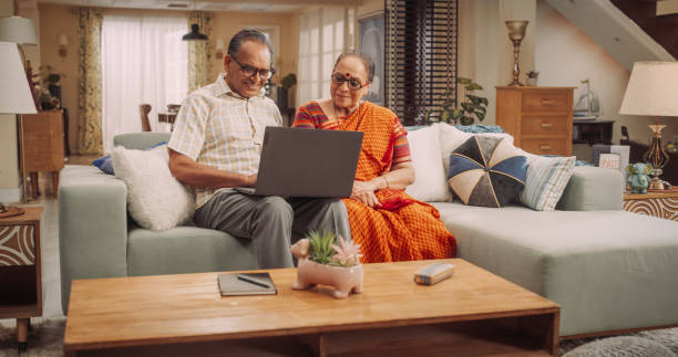 istock Elderly Couple Using Laptop at Home: Engaged in Joint Online Activities, from Researching Travel Destinations to Sharing Memorable Photos. Happy Older Couple Enjoying Retirement Actively. Medium 1560456070