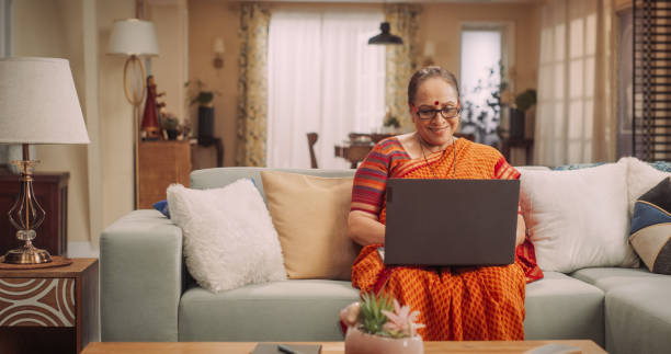 istock Indian Elderly Woman Using Laptop at Home: Exploring Online Information, Enjoying Entertainment, and Expanding Knowledge. Embracing Technology for Personal Growth. Medium Shot. 1560458175