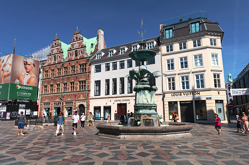 The famous Stork fountain and traditional old houses on the street in the center of Copenhagen, Denmark - July 20, 2023