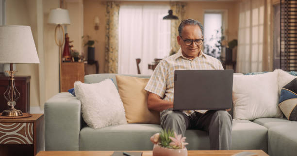 Elderly Indian Man Using Laptop at Home: Using Online Forums to Explore Interests, Delving into History, Arts, and Literature. Cultivating Wisdom and Sharing Stories on Social Media. Medium Static