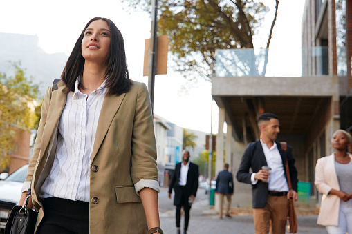 Young and happy businesswoman walking in the city
